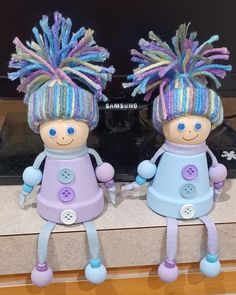 two little dolls with colorful hair are sitting next to each other on a counter top