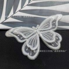 a white butterfly is sitting on top of a piece of fabric and it's wings are