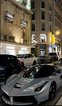 a row of cars parked on the side of a street next to tall buildings at night