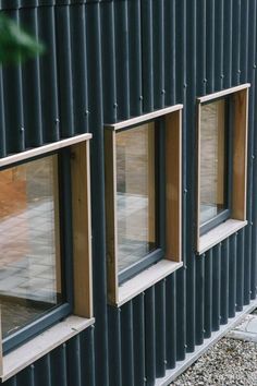 three windows on the side of a building with metal siding and wood trim around them