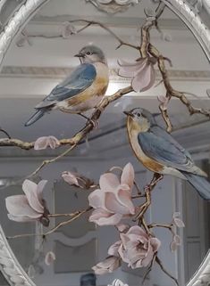 two birds are perched on the branch of a tree with pink flowers in front of it