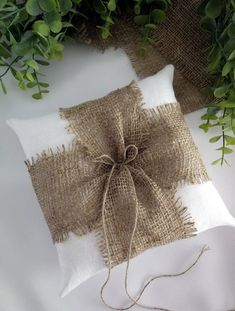 a white pillow with burlock tied to it and some green plants in the background