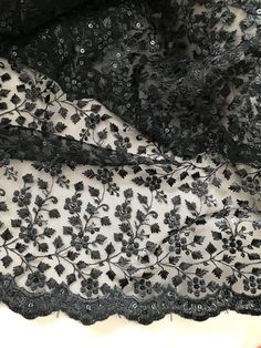 black lace with flowers on it is laying on a tablecloth that has been folded over