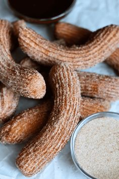 powdered sugar covered donuts next to a cup of coffee on a white tablecloth