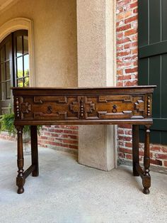 an old wooden table sitting in front of a brick building