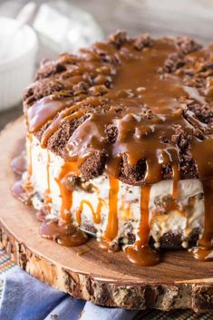 a cake covered in ice cream and caramel drizzles on a wooden board