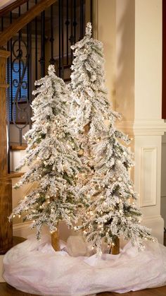 a white christmas tree is on display in front of a stair case and banister