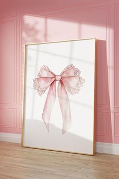 a pink bow is hanging on the wall next to a white framed art print in an empty room