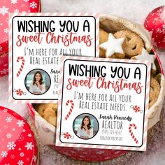 two christmas gift tags sitting on top of a red bowl filled with cookies and candy