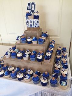 a table topped with lots of cupcakes covered in blue and white frosting