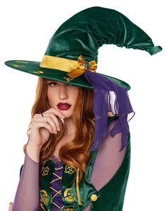 a woman wearing a green witch hat and purple dress with her hand on her chin