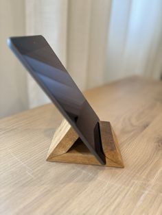 an electronic device is sitting on top of a wooden stand that sits on a table