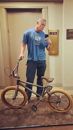 a man standing next to a bike holding a cell phone