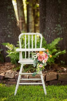 a white chair with flowers on it in the grass