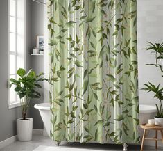 a bathroom with a green shower curtain next to a bathtub and potted plant