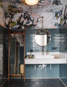 the bathroom is decorated in blue and white with floral wallpaper on the walls, along with a round mirror