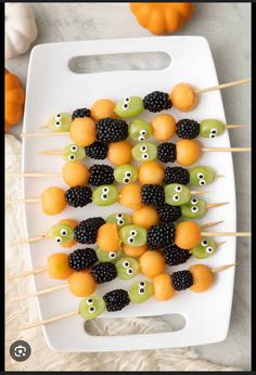 halloween fruit skewers on a white tray with blackberries and oranges in the background