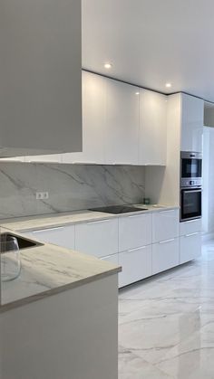 a kitchen with marble counter tops and white cabinets