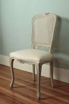 a white chair sitting on top of a hard wood floor next to a blue wall