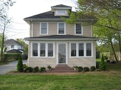 a two story house in the middle of a yard with trees and bushes around it