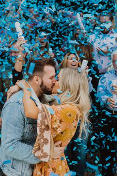 a man and woman kissing in front of confetti filled with blue streamers