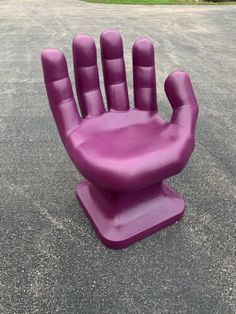 a purple plastic hand sitting in the middle of a parking lot on top of cement