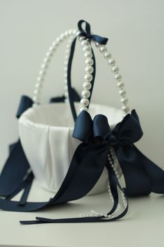 a white and blue basket with pearls on the side, tied to it's sides