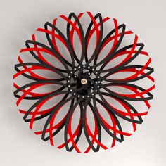 a clock with black and red designs on it's face next to a white wall