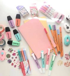 various stationery items laid out on top of a white surface, including pens and pencils