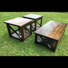 three wooden tables sitting on top of a lush green field