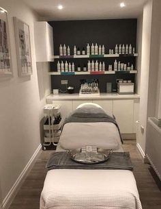 a spa room with two massage tables and shelves filled with bottles on the back wall