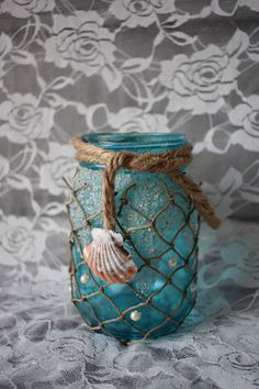 a blue glass jar with sea shells in it