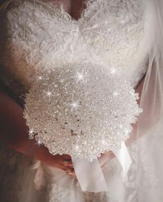 the bride is holding her wedding bouquet with pearls and sequins on it's back