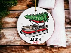 a personalized christmas ornament with a boat and pine tree on the front