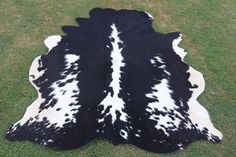 a black and white cowhide rug on grass