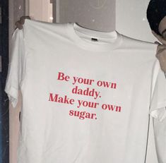 a man holding up a t - shirt that says be your own daddy make your own sugar