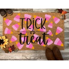 a door mat with the words trick or treat written on it next to fall leaves