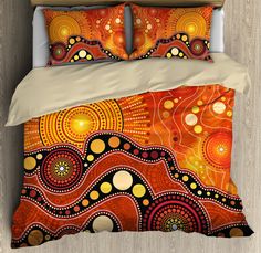 a bed with an orange and yellow comforter set on top of wooden flooring