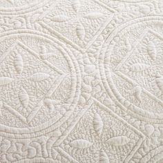 close up view of the white quilting on top of a bed sheet that has been made into an intricate pattern