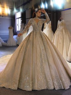 a woman in a wedding dress standing next to dresses on display at a bridal event