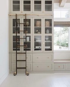 a kitchen with white cabinets and wooden ladders in it's centerpiece, along with a large window