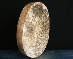 a brown and white plate sitting on top of a wooden table next to a black wall