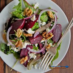 a salad with beets, feta cheese and walnuts on a white plate