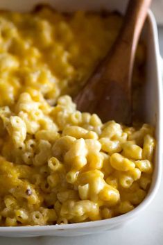 macaroni and cheese in a white casserole dish with a wooden spoon