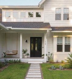 a white house with a black door and steps leading up to the front door,