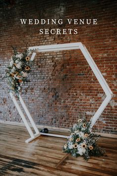 a wedding arch with flowers and greenery on the floor in front of a brick wall