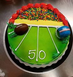 a football field cake is decorated with sprinkles and sports balls on it