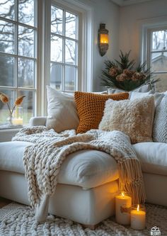 a living room filled with lots of white furniture and pillows on top of a couch