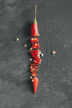 a red pepper is being sliced and placed on top of the other side, with peanuts scattered around it