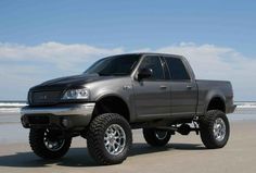 a gray truck parked on top of a sandy beach